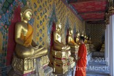 Bangkok - Mönch im Wat Arun vor goldenen Buddah-Statuen